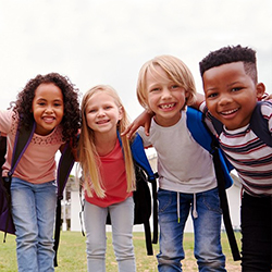 Four children, two Black and two White, standing with their arms around each other, smiling