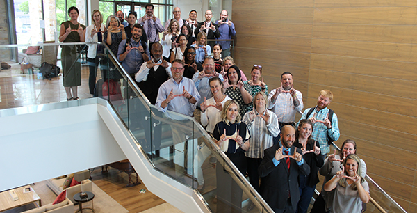 Photo of faculty standing on stairs, making a U shape wiht their hands