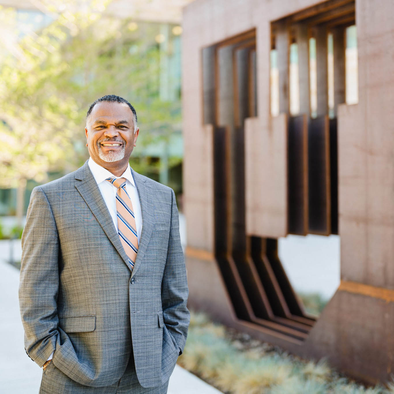 Photo of Dean Martell Teasley, smiling and looking at the camera, standing next to a copper block U